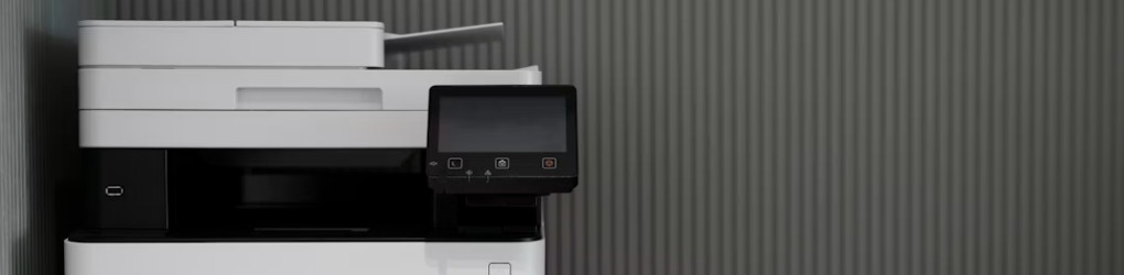 Vit multifunktionsskrivare med digital display framför en vägg med vertikala linjer.