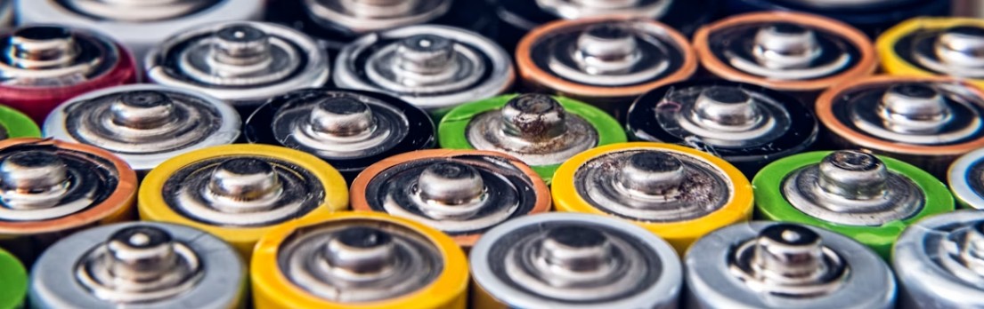 Närbild av AA-batterier i olika färger, några med rostiga eller slitna toppar