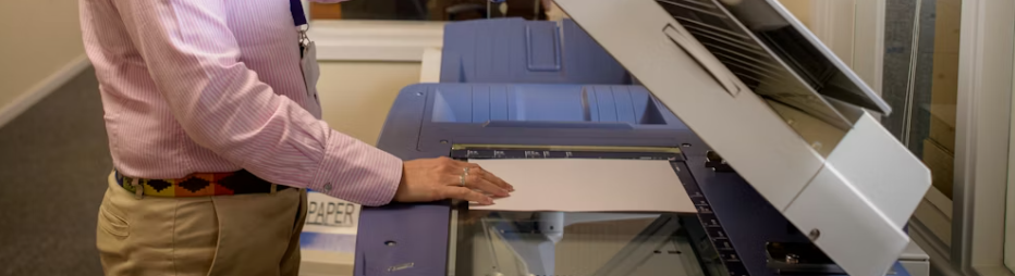 Person lägger ett ark på glaset i en skrivare för skanning.