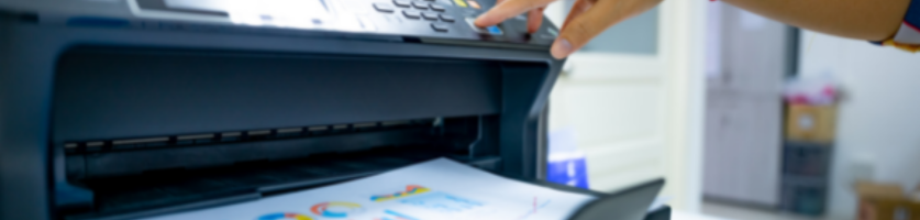 Skrivare som matar ut ett utskrivet dokument medan en hand trycker på kontrollpanelen.